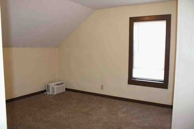 additional living space featuring baseboards, lofted ceiling, carpet flooring, and a wall mounted AC