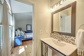 bathroom with vanity, decorative backsplash, and wood finished floors