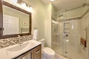 full bath with vanity, decorative backsplash, toilet, and a stall shower