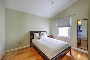 bedroom with wood finished floors, baseboards, and vaulted ceiling