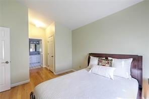 bedroom featuring baseboards, wood finished floors, and vaulted ceiling