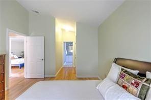 bedroom featuring wood finished floors, baseboards, and vaulted ceiling