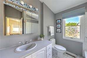 bathroom featuring vanity, vaulted ceiling, tile patterned floors, toilet, and baseboard heating