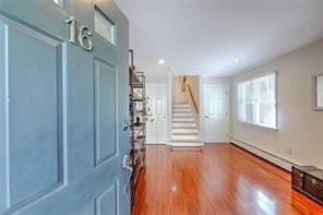 entrance foyer with a baseboard radiator, wood finished floors, and stairs