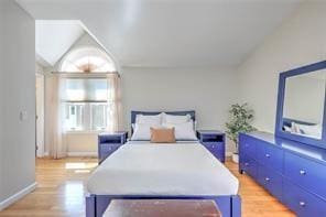 bedroom featuring light wood-type flooring and vaulted ceiling