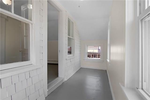 hall featuring baseboard heating, concrete floors, and vaulted ceiling