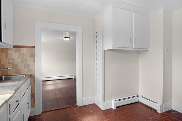 kitchen featuring white cabinetry, light countertops, a baseboard heating unit, and a sink