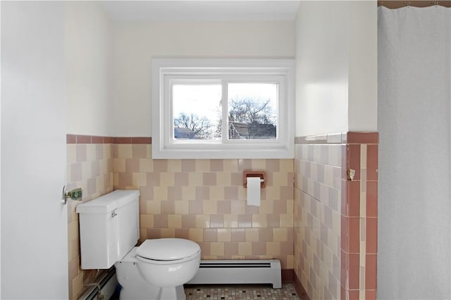 bathroom featuring a baseboard heating unit, tile walls, toilet, and wainscoting