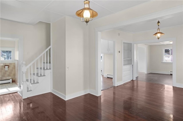 spare room featuring a baseboard heating unit, baseboards, hardwood / wood-style floors, and stairs