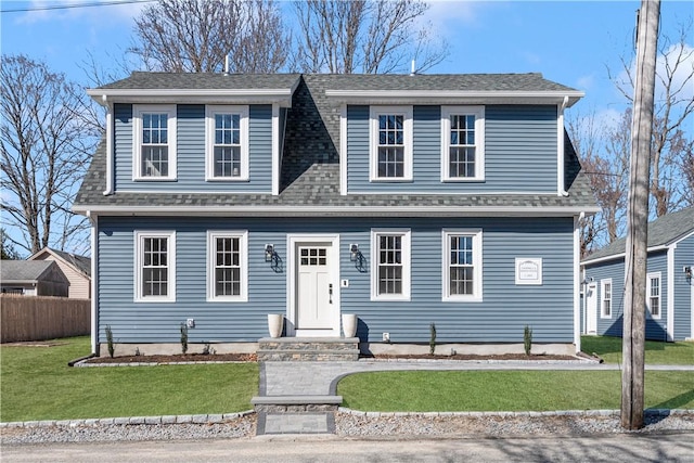 view of front of house featuring a front yard, fence, and a shingled roof