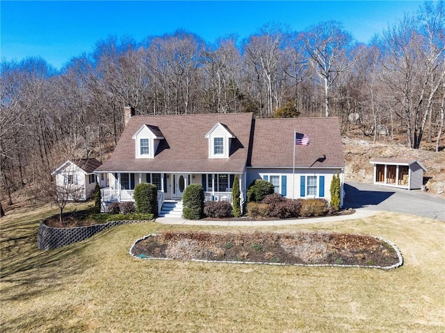 cape cod home with aphalt driveway, covered porch, a chimney, and a front lawn