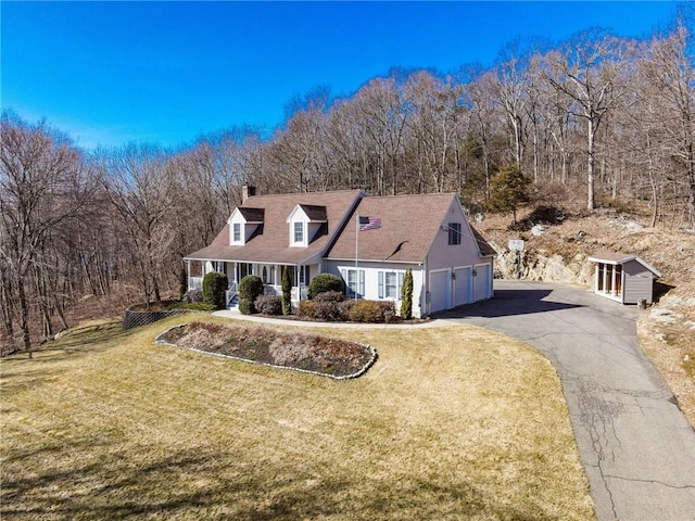 cape cod house with aphalt driveway, a porch, a front yard, a chimney, and a garage