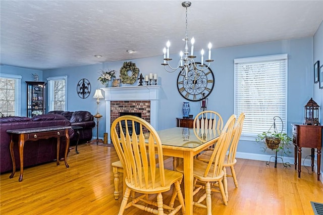 dining room with light wood finished floors, a fireplace, and a textured ceiling