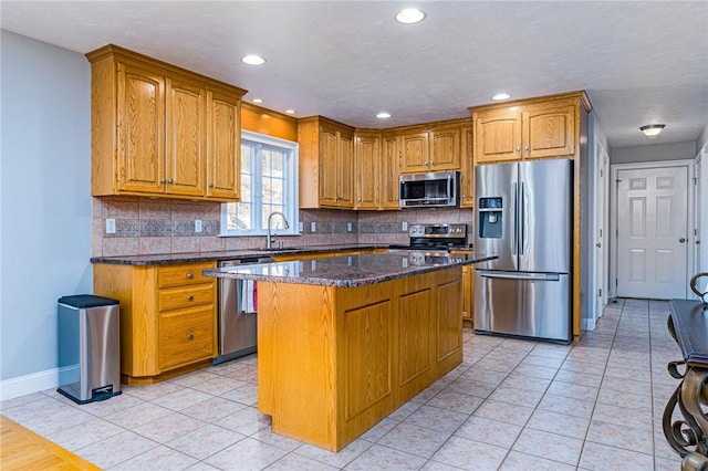 kitchen featuring a sink, appliances with stainless steel finishes, dark stone countertops, and light tile patterned floors