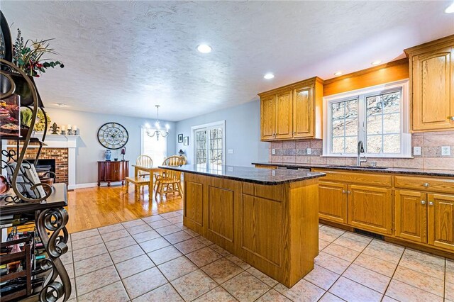 kitchen with tasteful backsplash, a center island, light tile patterned floors, a textured ceiling, and a sink