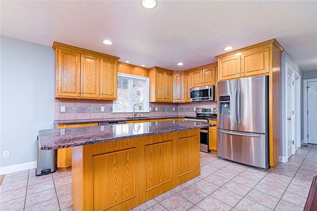 kitchen with dark stone counters, backsplash, light tile patterned flooring, and appliances with stainless steel finishes