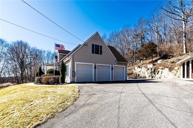 view of side of home featuring a lawn, driveway, and a garage