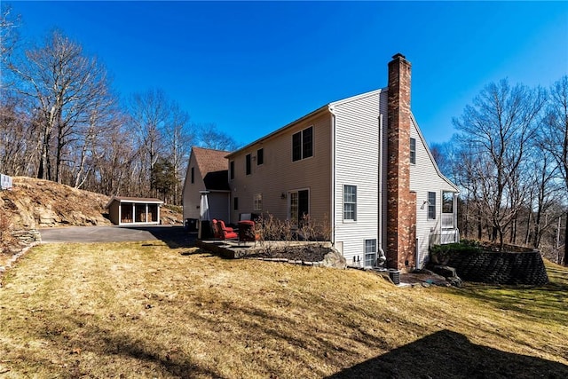 back of property with a patio, a lawn, and a chimney