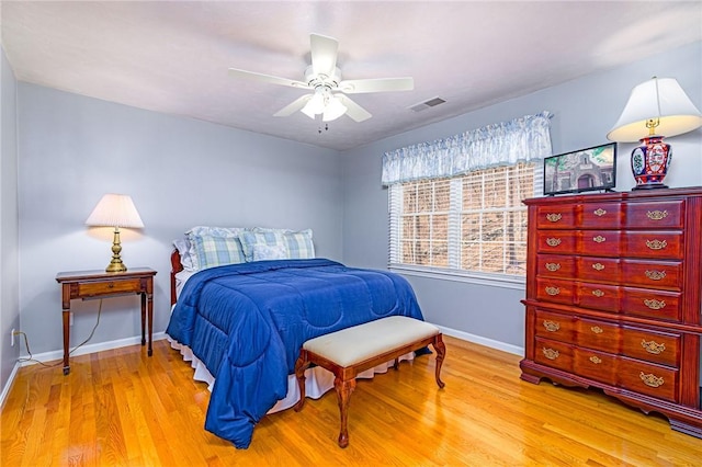 bedroom featuring ceiling fan, visible vents, baseboards, and wood finished floors