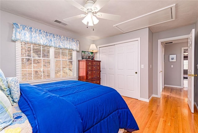 bedroom featuring a closet, visible vents, multiple windows, and light wood-style floors