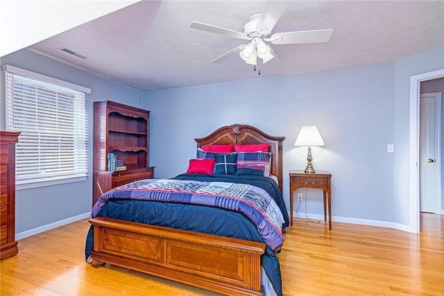 bedroom with ceiling fan, wood finished floors, visible vents, and baseboards