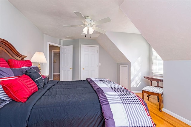 bedroom featuring a ceiling fan, vaulted ceiling, light wood-style floors, and baseboards