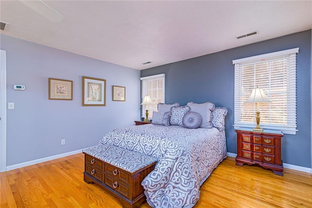 bedroom with light wood-style floors, visible vents, and baseboards