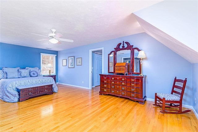 bedroom with baseboards, a textured ceiling, wood finished floors, and vaulted ceiling