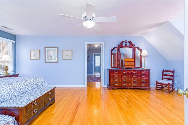 bedroom featuring visible vents, baseboards, lofted ceiling, light wood-style flooring, and a ceiling fan