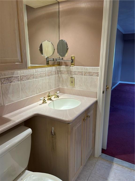 bathroom with toilet, tasteful backsplash, crown molding, tile patterned flooring, and vanity