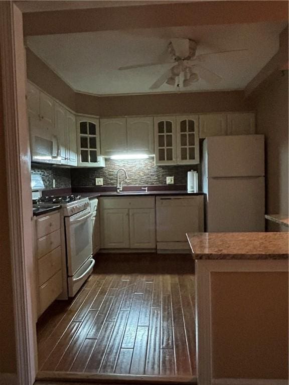 kitchen with a sink, glass insert cabinets, white appliances, and dark wood-style flooring