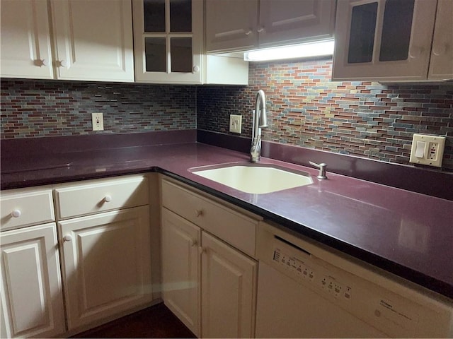 kitchen featuring a sink, tasteful backsplash, white cabinets, and white dishwasher