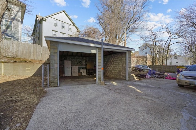 view of parking / parking lot featuring fence and a garage