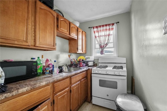 kitchen featuring a sink, brown cabinets, white range with gas stovetop, and black microwave