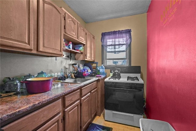 kitchen featuring open shelves, a sink, a textured ceiling, gas range, and light wood-type flooring