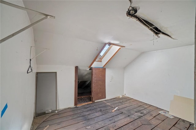 additional living space featuring vaulted ceiling with skylight and wood-type flooring