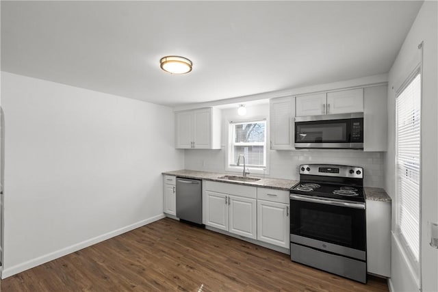 kitchen featuring dark wood-type flooring, baseboards, appliances with stainless steel finishes, and a sink