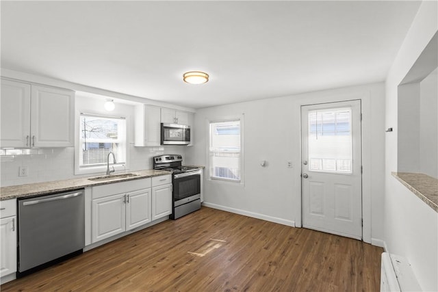 kitchen with dark wood-style floors, white cabinetry, stainless steel appliances, and a sink