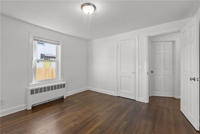 unfurnished bedroom with baseboards, radiator, and dark wood-style floors