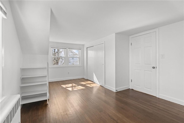 unfurnished bedroom featuring a closet, baseboards, radiator heating unit, and hardwood / wood-style flooring