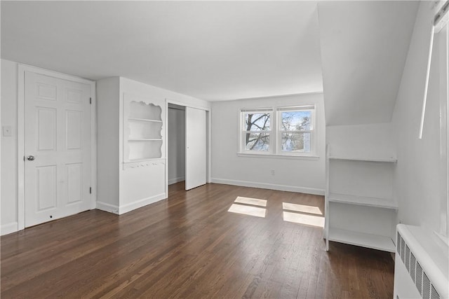 unfurnished bedroom with a closet, baseboards, radiator, and wood finished floors