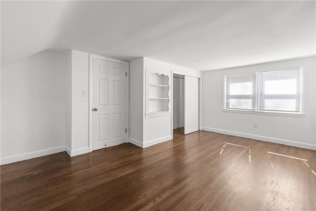 unfurnished bedroom with vaulted ceiling, baseboards, and dark wood-style flooring