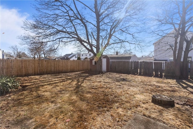 view of yard with an outdoor structure, a storage unit, and a fenced backyard