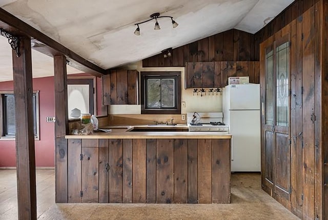 kitchen featuring a sink, freestanding refrigerator, a peninsula, light countertops, and vaulted ceiling