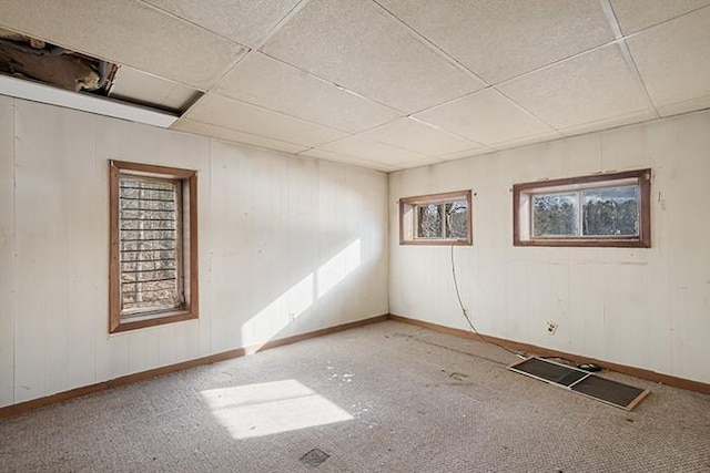 spare room featuring a paneled ceiling and baseboards