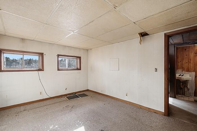 interior space with carpet, baseboards, and a drop ceiling