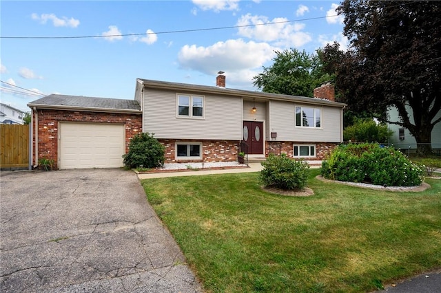 split foyer home with fence, an attached garage, a chimney, a front lawn, and brick siding