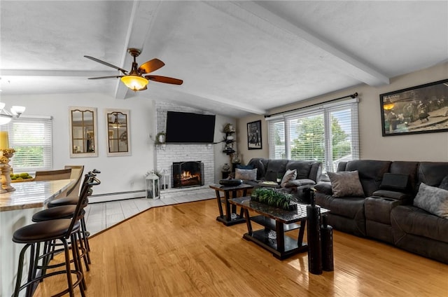 living room featuring ceiling fan with notable chandelier, a fireplace, light wood finished floors, a baseboard radiator, and vaulted ceiling with beams