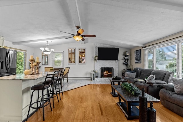 living room with plenty of natural light, light wood-style flooring, a brick fireplace, and a baseboard radiator