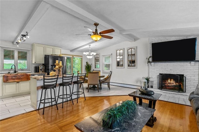 living area with a wealth of natural light, a fireplace, vaulted ceiling with beams, and a baseboard radiator